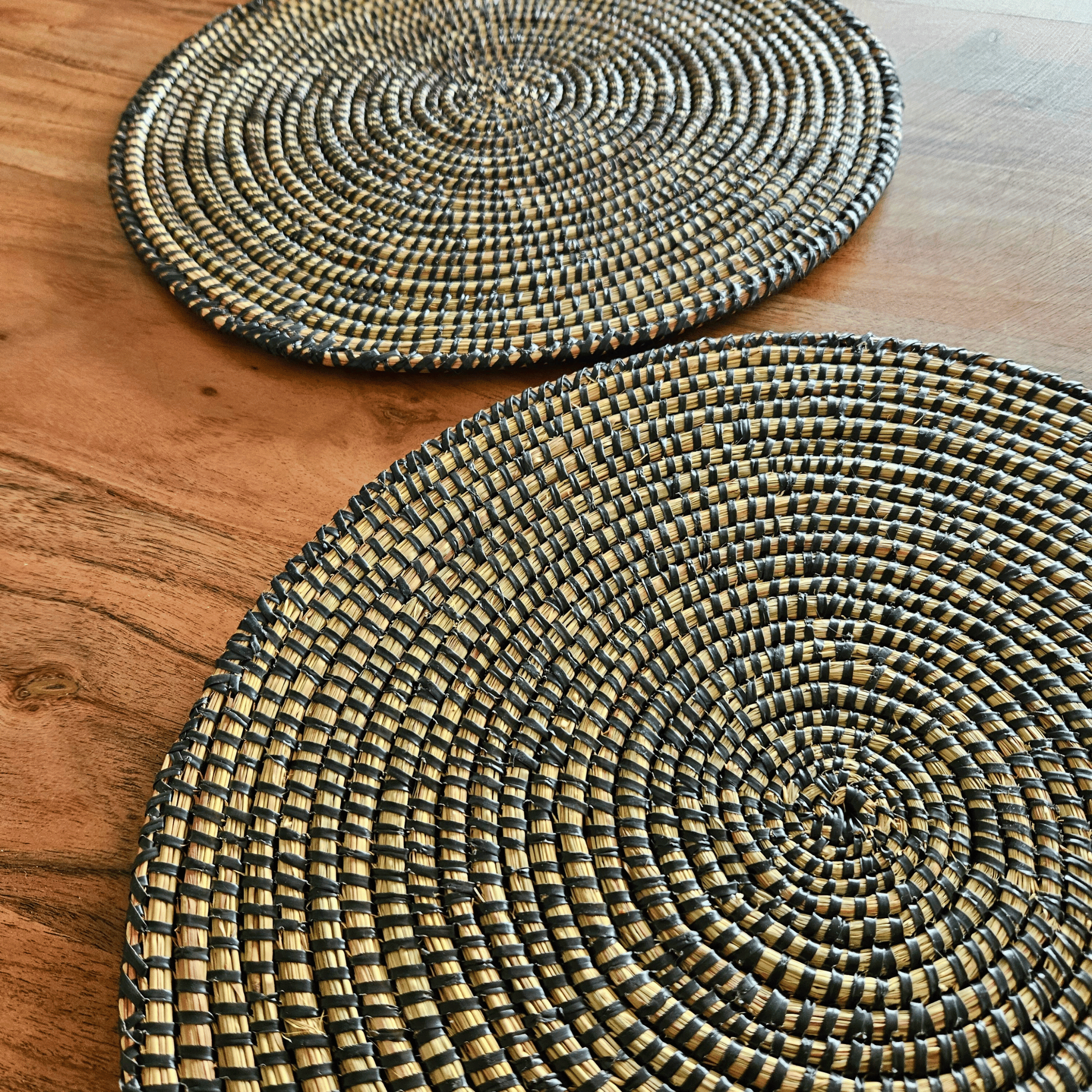 Image de deux sets de table noirs ronds tressés en fibres naturels