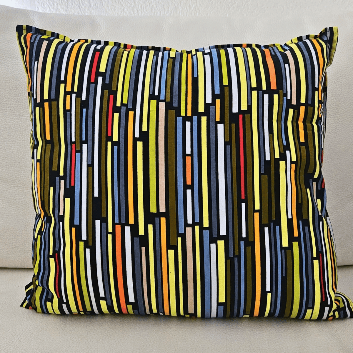 Image d'un coussin en tissu wax multicolore posé sur un canapé blanc