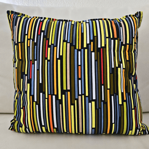 Image d'un coussin en tissu wax multicolore posé sur un canapé blanc