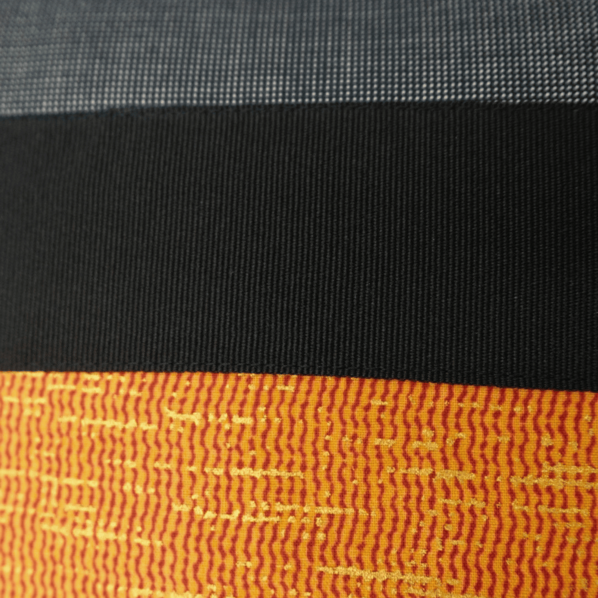 Image des détails d'un tissu orange, noir et gris pour coussin