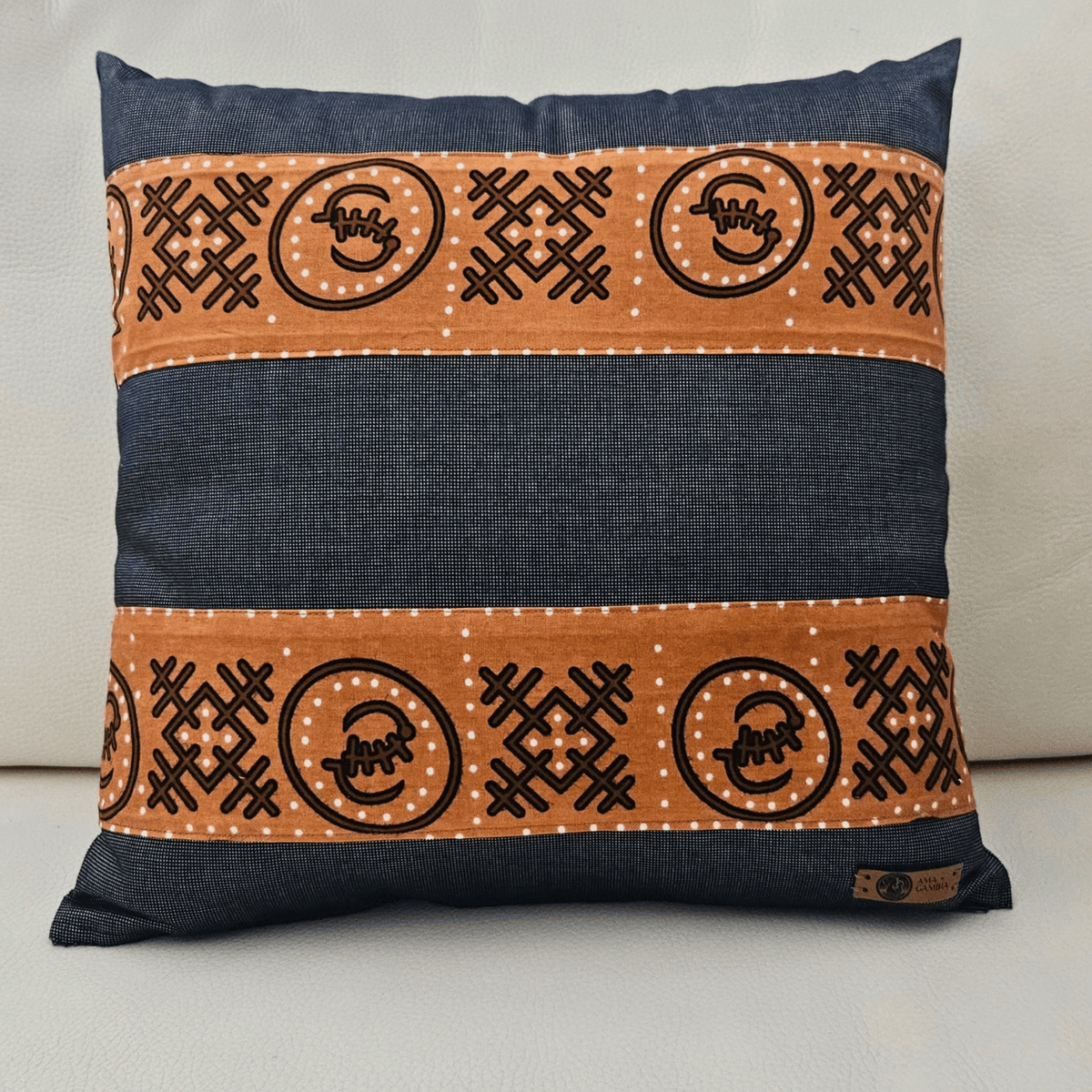 Image d'un coussin avec tissu wax brun et tissu gris uni posé sur un canapé