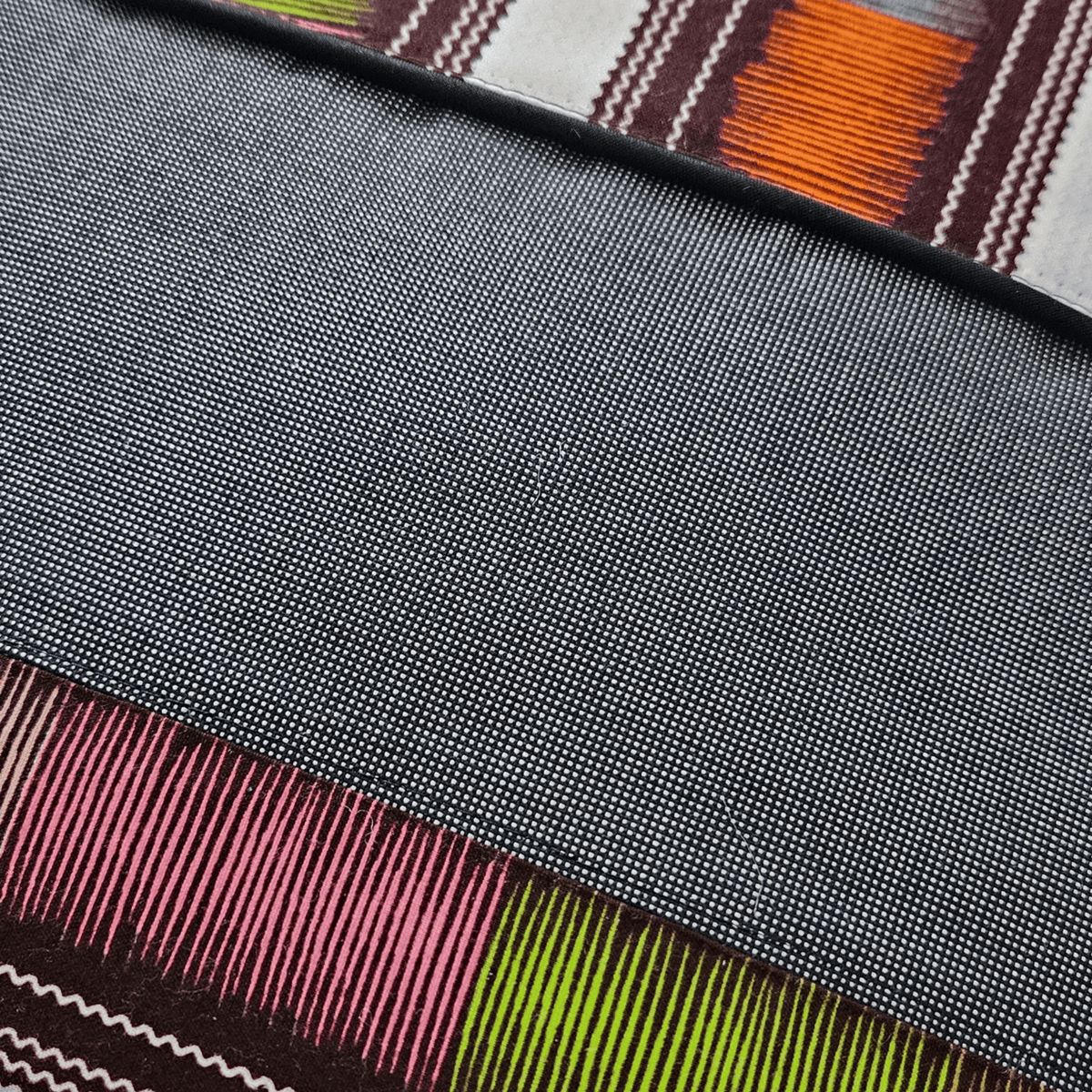 Image des détails d'un coussin tissu wax et tissu gris uni