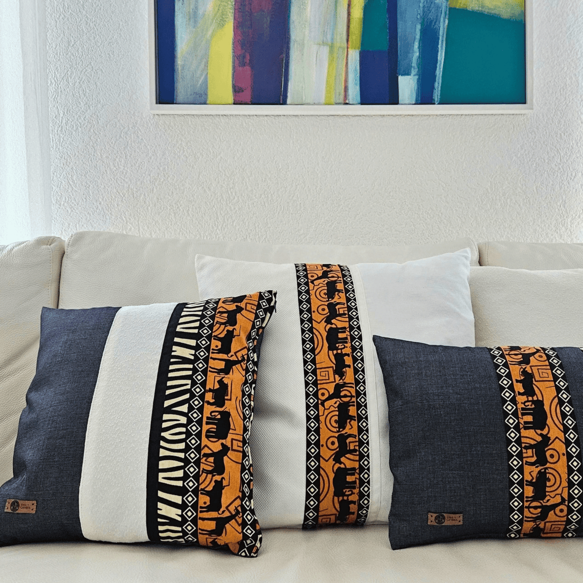 Image de trois coussins en wax avec motifs d'animaux dans un salon moderne