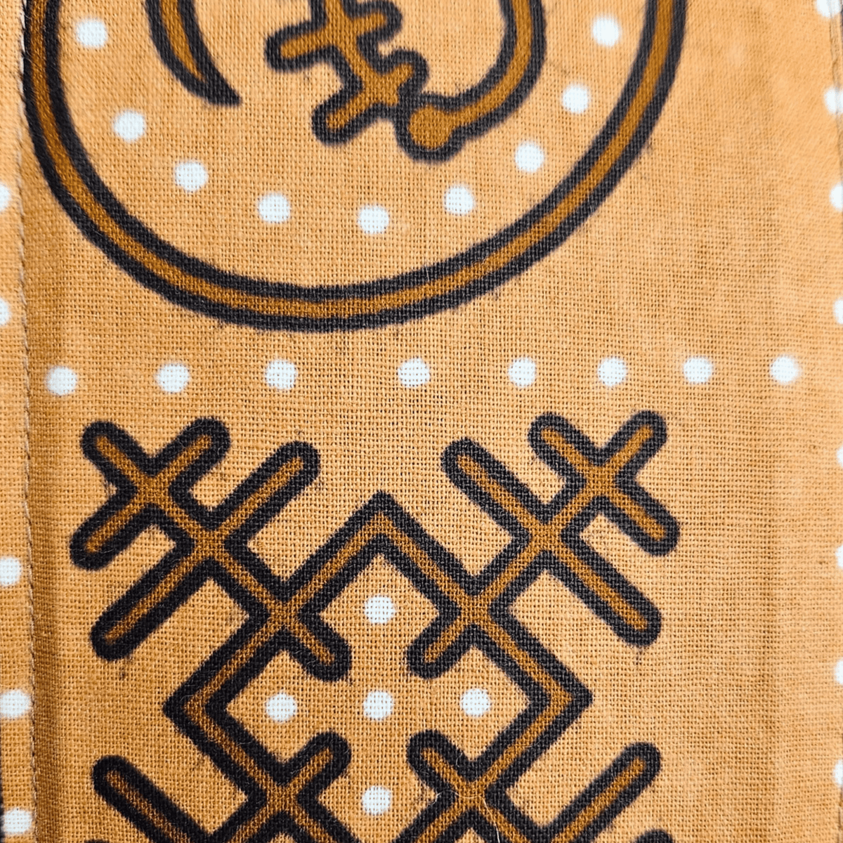 Image des détails d'un tissu en wax brun avec motifs graphiques